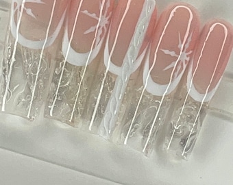 May include: Set of six pink and white press-on nails with a white starburst design.