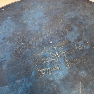 May include: Close-up of a distressed blue surface with embossed text. The text includes the name "Gondolf" in an elegant script, along with "Rue Serpenoise" and "15 Romer Strasse". The surface has a textured, aged appearance.