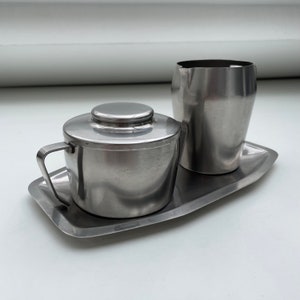 May include: A silver sugar bowl with a lid and a silver creamer on a silver tray.