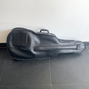 Puede incluir: Estuche de guitarra negro con asa y un pequeño bolsillo en el lateral.