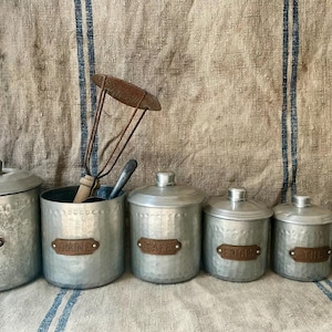 Un juego a juego de seis botes de cocina vintage franceses de metal martillado.