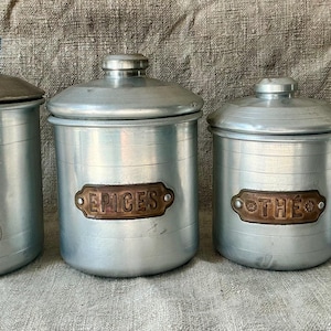 Un juego a juego de cuatro botes de cocina metálicos franceses de estilo vintage.