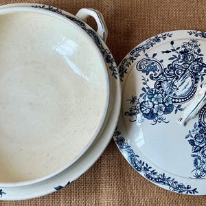 Puede incluir: Cuenco de cer&aacute;mica color crema con tapa a juego. La tapa y el borde del cuenco est&aacute;n decorados con un estampado floral azul. El cuenco tiene dos asas y la tapa tiene un asa.