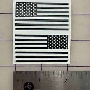 May include: Two black and white American flag decals, each measuring approximately 2 inches by 3 inches. The decals are printed on a white background.