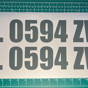 May include: Two rows of gray vinyl letters spelling out "FL 0594 ZW" on a white background. The letters are approximately 3 inches tall.