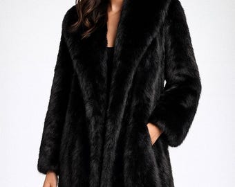 May include: A long, black faux fur coat with a wide lapel collar. The coat has long sleeves and pockets. The model is wearing black pants. The coat is a classic outerwear piece.