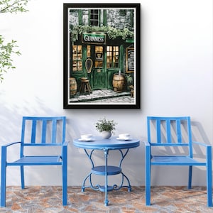 a cozy outdoor seating area with a Guinness pub in the background, complete with a table and chairs. The pub has a green facade and a sign that reads "GUINNESS", creating a warm and inviting atmosphere. The seating area is adorned with two blue chairs, and a small blue table is situated between them. A potted plant is placed on the table, adding a touch of greenery to the scene. The overall setting appears to be a comfortable and relaxing space, perfect for enjoying a pint of Guinness.