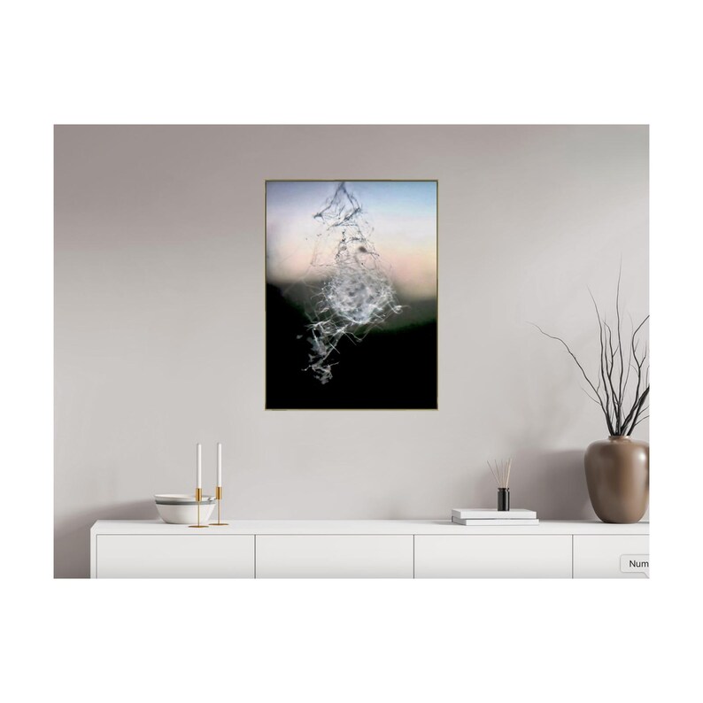 May include: A framed abstract art print with a central, dynamic composition of white, crystalline forms against a blurred backdrop of black, green, and a soft gradient of blue and peach. The artwork is displayed on a white cabinet.