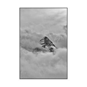 May include: Black and white photograph of a mountain peak emerging from a sea of clouds. The mountain is dark and textured, contrasting with the soft, billowy clouds that surround it. The image is framed in a black border.