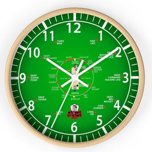 May include: A green and white clock with a cricket field design. The clock face shows the positions of fielders on a cricket pitch. The clock face also includes the text "street cricket 24x7".