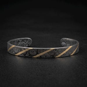 Bracciale rigido in acciaio di Damasco forgiato a mano con inserto in ottone.