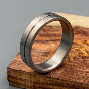 May include: A silver-toned metal ring with a brushed finish and a single, thin groove around the band.