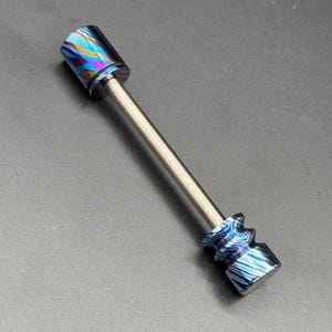 May include: A decorative bottle stopper with a stainless steel rod and two ends with a colorful, marbled design in shades of blue, purple, and orange. The stopper is designed to fit into a bottle.