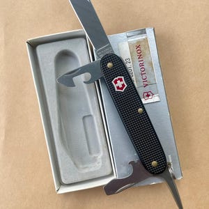 Victorinox Pioneer 93 mm Alox noir rouge avec bouclier (0.8201.23) - Très bon état