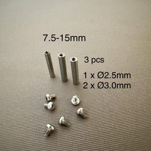 May include: Three silver-colored metal cylindrical standoffs and five small silver-colored metal screws. Text on the image reads: 7.5-15mm, 3 pcs, 1 x Ø2.5mm, 2 x Ø3.0mm. The components are arranged on a textured surface.