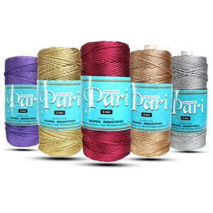 May include: Five spools of 3 mm macrame cord in various colors: purple, gold, burgundy, tan, and silver. Each spool has a label with the text "Pari" and "3 mm". The labels also include the manufacturer's name, "MADHU INDUSTRIES".