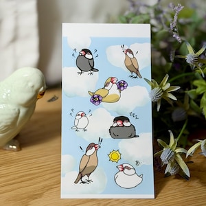 May include: A rectangular sticker sheet featuring cartoon birds with various expressions against a blue sky background with white clouds. The birds are in shades of gray, brown, and white, with some holding flowers. A yellow sun is also depicted.