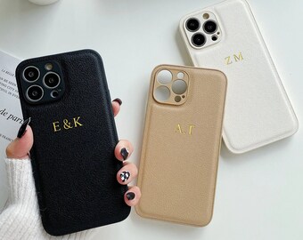 May include: Three different phone cases with personalised initials. The cases are black, beige and white with a textured finish. The initials are in gold lettering.