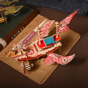 May include: A red and white wooden ship with intricate details, including a propeller, sails, and a gold chain. The ship is on a brown background with the text "Top Secret" visible.