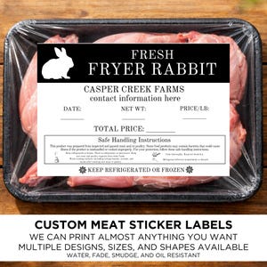 May include: A package of fresh fryer rabbit, labeled with "FRESH FRYER RABBIT" and "CASPER CREEK FARMS." The label includes space for date, net weight, and price. The package is wrapped in clear plastic and sits on a black tray. The bottom of the image reads "CUSTOM MEAT STICKER LABELS."