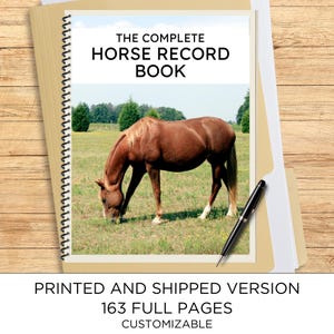May include: A spiral-bound record book titled THE COMPLETE HORSE RECORD BOOK featuring a brown horse grazing in a field on the cover. The book includes 163 full pages and is accompanied by a black pen, presented on a light wood-grain surface.