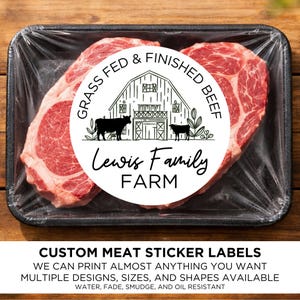 May include: Two raw beef steaks in a black tray, sealed with clear plastic wrap. Each steak has a circular label that reads "Grass Fed & Finished Beef" and "Lewis Family Farm" with a barn and cow illustration. The bottom text says "Custom Meat Sticker Labels".
