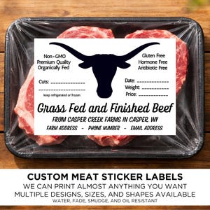 May include: A package of raw beef steaks in a black tray, wrapped in clear plastic. A white label features a black longhorn silhouette, text about the beef's quality, and space for details. The label also advertises custom meat sticker labels.