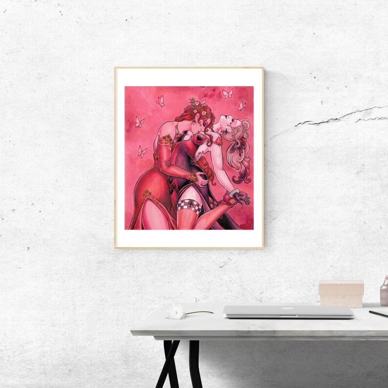 Pu&ograve; includere: Un'illustrazione incorniciata di due donne in abiti rossi che si baciano. Lo sfondo &egrave; un acquerello rosa con farfalle bianche.