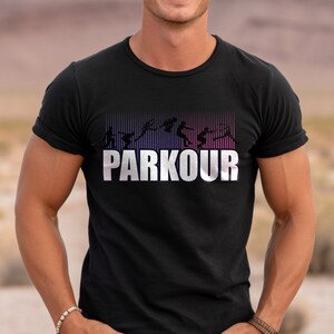 May include: Black t-shirt with a white graphic of a silhouette of a person doing parkour. The graphic has a gradient of pink and purple stripes behind it. The text "PARKOUR" is in white letters below the graphic.
