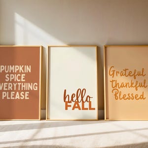 Peut inclure: Trois impressions d'art encadrées avec du texte sur le thème de l'automne. La première impression est de couleur marron avec le texte "PUMPKIN SPICE EVERYTHING PLEASE". La deuxième est blanc cassé avec "hello FALL". La troisième est pêche avec "Grateful Thankful Blessed".