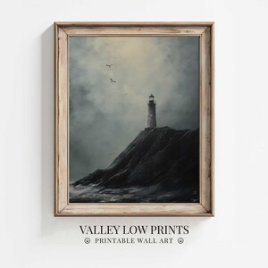 May include: A framed print depicting a lighthouse on a cliff, under a cloudy sky. The artwork is in grayscale and framed in wood. The print is labeled "VALLEY LOW PRINTS PRINTABLE WALL ART".