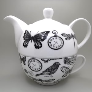 May include: A white teapot and teacup set with a black and white design featuring butterflies, clocks, and a bird. The teapot has a round body and a handle on the side. The teacup has a handle on the side and a matching design.