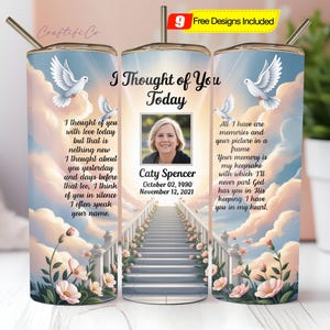 May include: A personalized memorial tumbler with a photo of Caty Spencer, dates, and a poem. The design features doves, a staircase to the sky, and floral accents. The tumbler includes a straw and a lid.