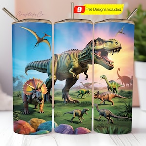 Könnte beinhalten: Ein Edelstahlbecher mit einem Dinosaurier-Design, darunter ein T-Rex und ein Triceratops, vor blauem Himmel und grüner Landschaft. Der Becher hat einen silbernen Strohhalm und den Text "Craftiful Co.".