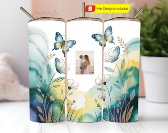 May include: A white tumbler with a watercolor design featuring blue butterflies, flowers, and foliage. The design includes a photo of a mother and child. The tumbler has a silver straw and the text "Craftiful Co."