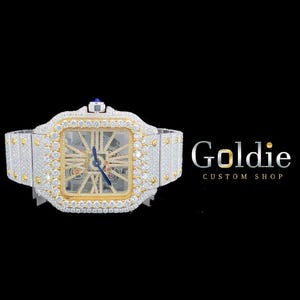 May include: A luxury wristwatch with a square face, encrusted with diamonds and gold accents. The watch features a skeleton dial, a blue hand, and a diamond-studded band. The brand name "Goldie Custom Shop" is displayed in the image.