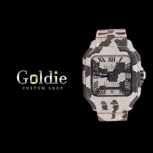 May include: A luxury wristwatch with a black and white camouflage design. The watch face features Roman numerals and the date. The watch is from Goldie Custom Shop, as shown by the logo on the left.