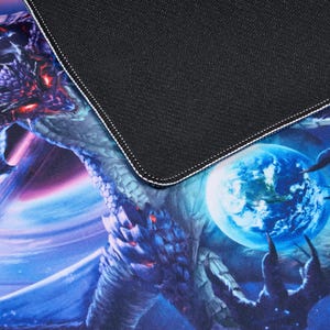 May include: A black and blue mouse pad with a dragon design. The dragon is holding a blue planet in its claws. The background is a galaxy with stars and planets.
