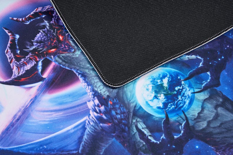 May include: A black and blue mouse pad with a dragon design. The dragon is holding a blue planet in its claws. The background is a galaxy with stars and planets.
