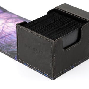 May include: A black deck box with a gray fabric exterior and a black interior. The box has a stitched seam around the edges and the word "RADIANT" is printed on the front.