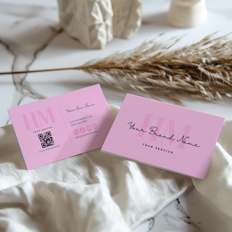 Op de afbeelding: Twee roze visitekaartjes met de tekst "HM YOUR SERVICE" en een QR-code op de ene kaart en "Your Brand Name YOUR SERVICE" op de andere kaart.