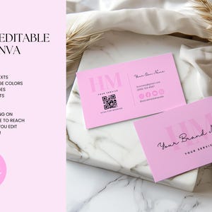 Op de afbeelding: Twee roze visitekaartjes met de tekst "HM" en "Your Brand Name" in zwart. De kaartjes liggen op een wit marmeren oppervlak met een gedroogde bloemstengel.