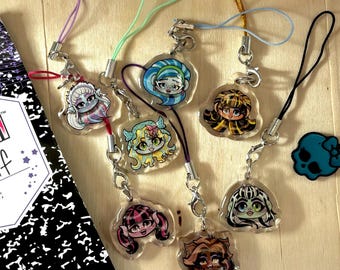 May include: Eight colorful character charms on clear plastic keychains with black, purple, blue, green, and red cords. The charms feature cartoon characters with different hairstyles and expressions.