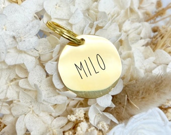 May include: Gold round dog tag with the name "MILO" engraved on it.