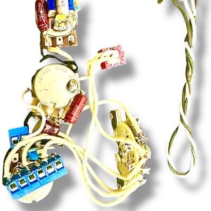 May include: Close-up of electronic components, including capacitors, resistors, and wiring. The components are various colors, including red, blue, and gold. The wiring is cream-colored and twisted. The background is white.