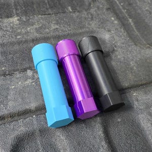 Puede incluir: Tres objetos cil&iacute;ndricos en azul, morado y negro. Cada uno tiene una base hexagonal y una parte superior texturizada. Los objetos azules y morados tienen un acabado brillante, mientras que el negro tiene un acabado mate. Los objetos est&aacute;n dispuestos en diagonal.