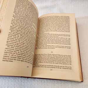 Peut inclure: Un livre reli&eacute; ouvert avec des pages couleur cr&egrave;me et du texte imprim&eacute; en noir. La page de gauche porte le num&eacute;ro 310 et la page de droite le num&eacute;ro 311, commen&ccedil;ant par le chiffre romain II et un paragraphe sur le prince Nikola&iuml;.
