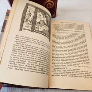 Peut inclure: Un livre reli&eacute; ouvert intitul&eacute; Crime et Ch&acirc;timent avec des pages couleur cr&egrave;me et du texte noir. La page de gauche pr&eacute;sente un dessin au trait en noir et blanc d'une personne regardant par une fen&ecirc;tre, tandis que la page de droite contient du texte.