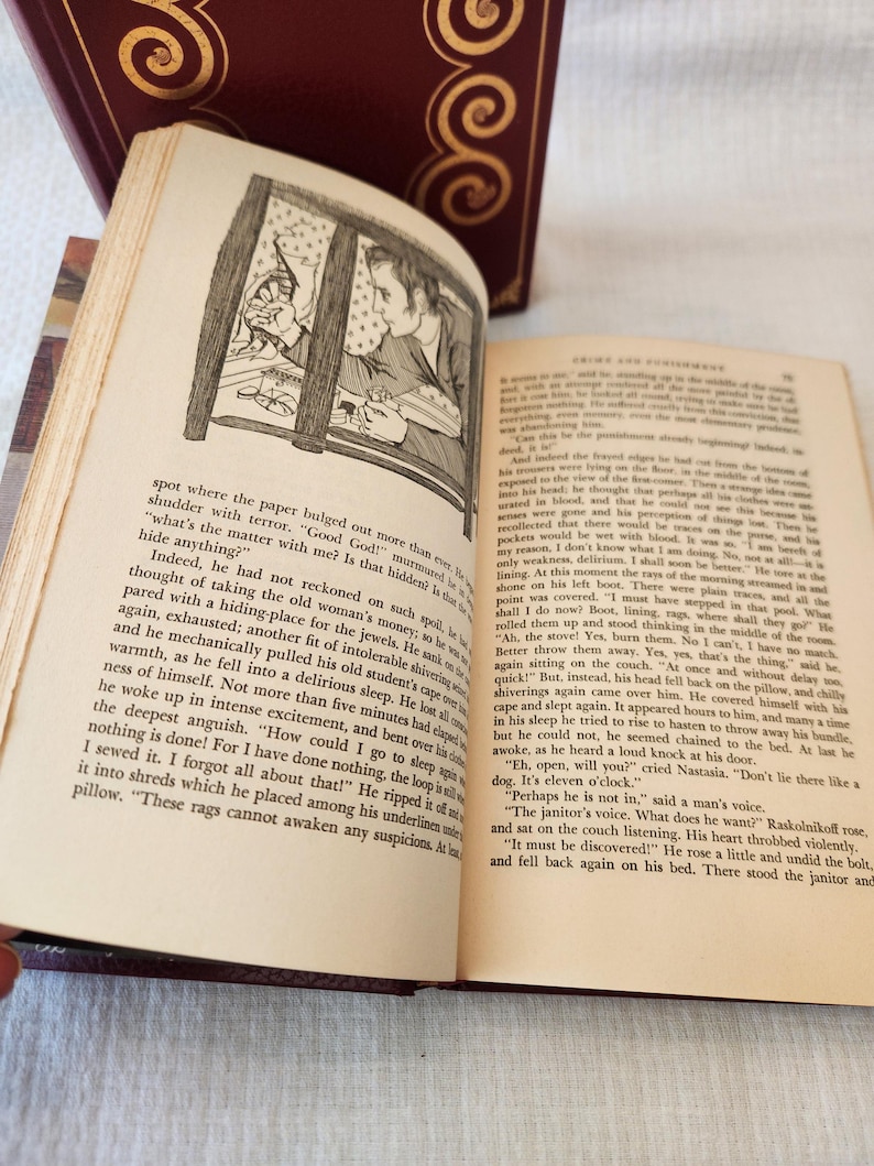 Peut inclure: Un livre reli&eacute; ouvert intitul&eacute; Crime et Ch&acirc;timent avec des pages couleur cr&egrave;me et du texte noir. La page de gauche pr&eacute;sente un dessin au trait en noir et blanc d'une personne regardant par une fen&ecirc;tre, tandis que la page de droite contient du texte.