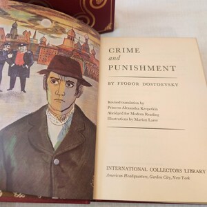 Peut inclure: Un livre reli&eacute; intitul&eacute; Crime and Punishment de Fyodor Dostoevsky, publi&eacute; par International Collectors Library. La page ouverte pr&eacute;sente une illustration d'un homme au chapeau et une sc&egrave;ne urbaine, avec le texte d&eacute;taillant la traduction et l'illustrateur.